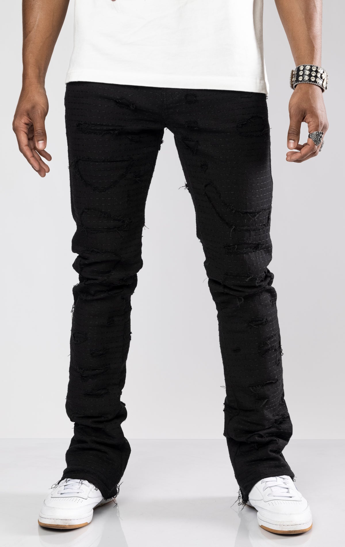Jet black distressed denim jeans with ripped details and a stacked fit at the ankle. 