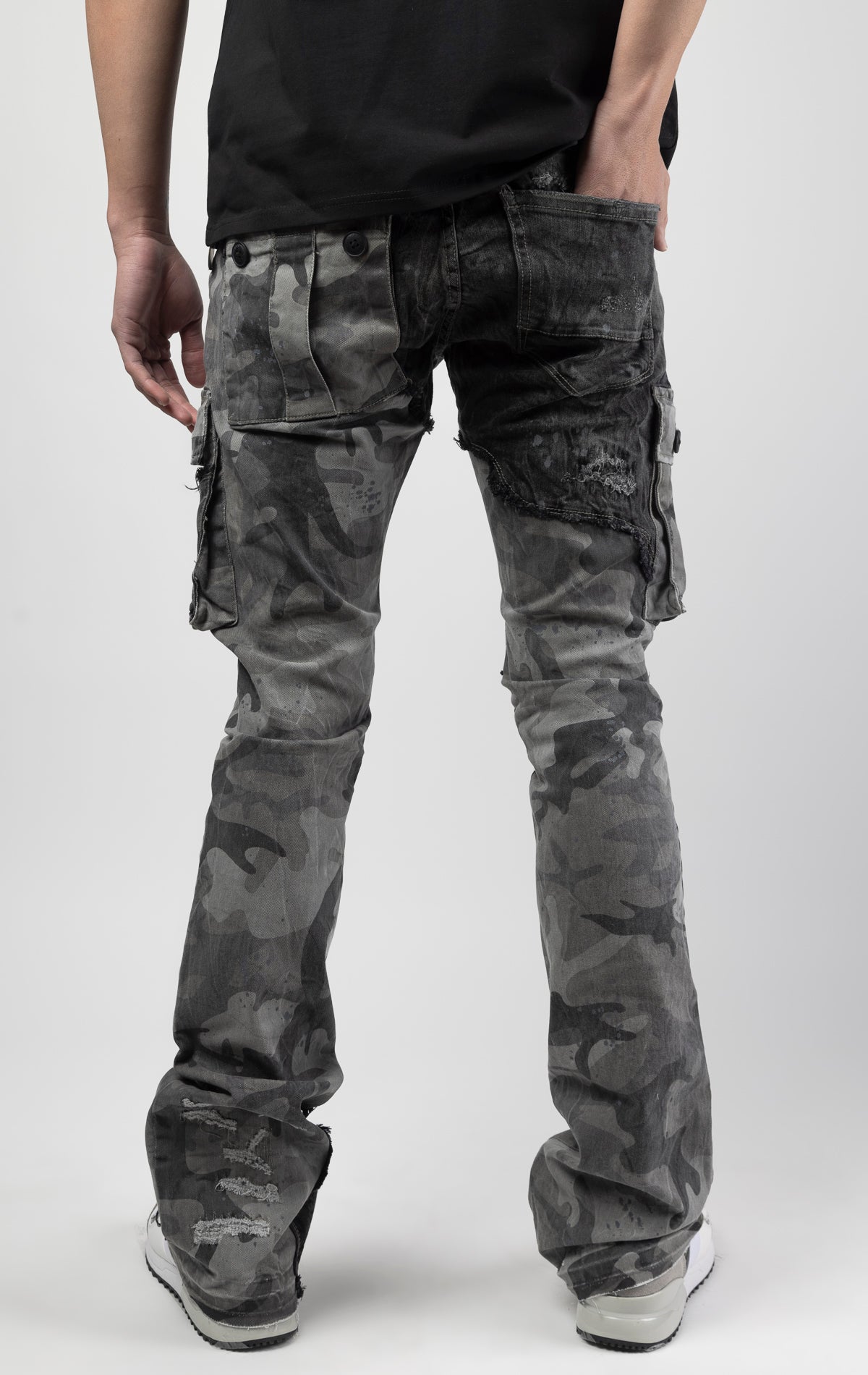 Black camo Extended length flare pant with a regular rise for maximum stacks. Skinny fit with hand-smearing and speckled paint splatter throughout. Rip and repair detailing, accompanied by cut & sewn woodland camouflage twill patches. Stitching repairs and deep front pocket bags, perfect for large smart phones.