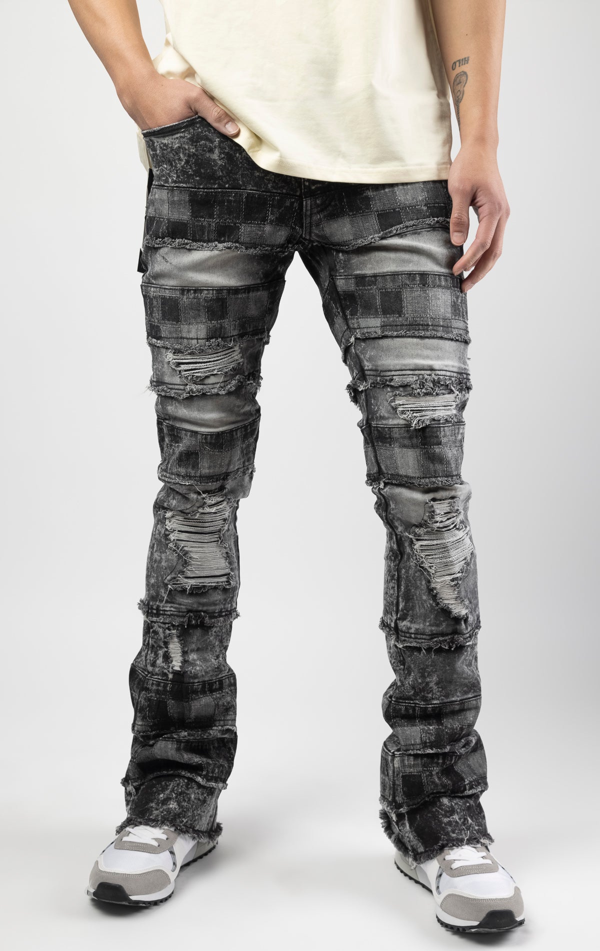 Black wash iconic stacked jeans crafted from high-quality, durable denim fabric consisting of 98% cotton and 2% spandex with a semi flare silhouette and a length of 35"-37". Featuring a distinctive ripped and repair design with pocket patches and a multi-tone dye throughout, these urban-inspired pants are true to size