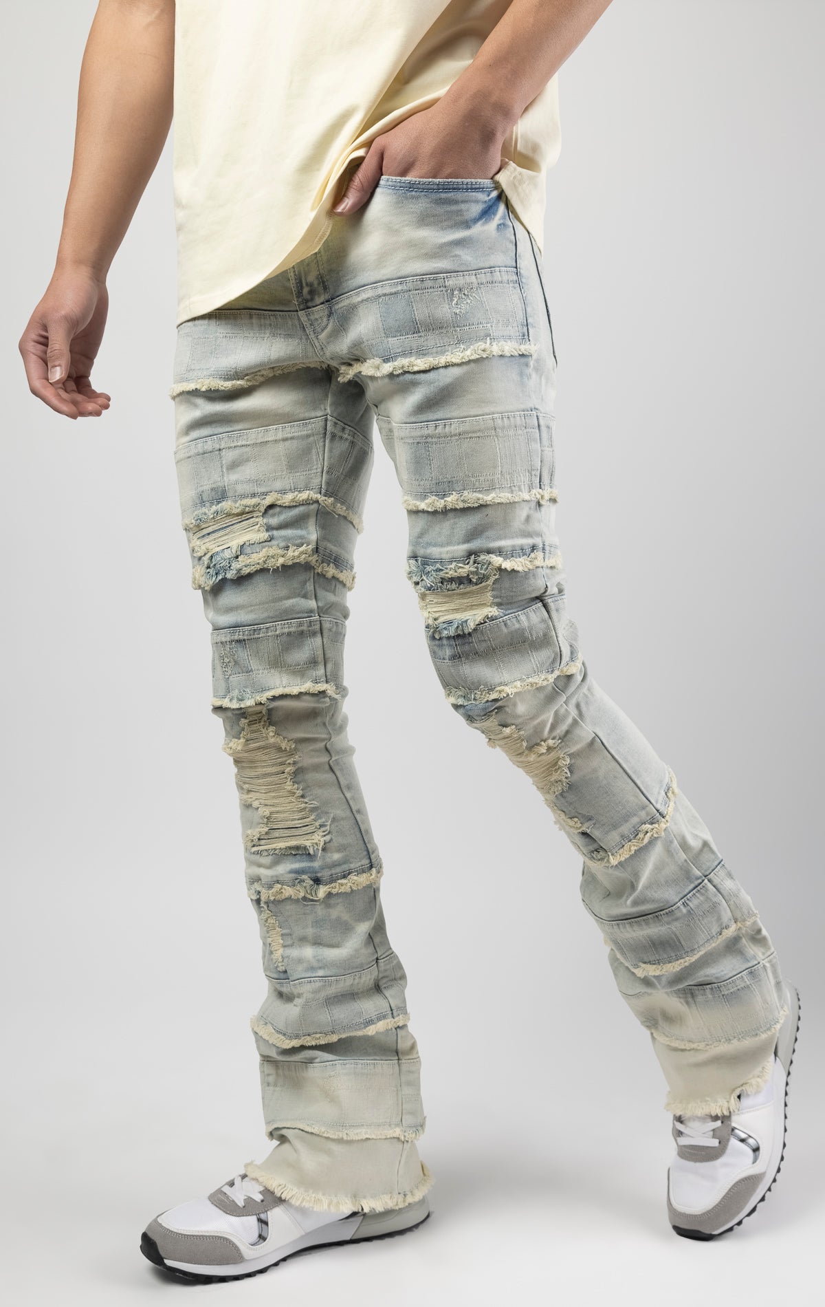 Light wash iconic stacked jeans crafted from high-quality, durable denim fabric consisting of 98% cotton and 2% spandex with a semi flare silhouette and a length of 35"-37". Featuring a distinctive ripped and repair design with pocket patches and a multi-tone dye throughout, these urban-inspired pants are true to size