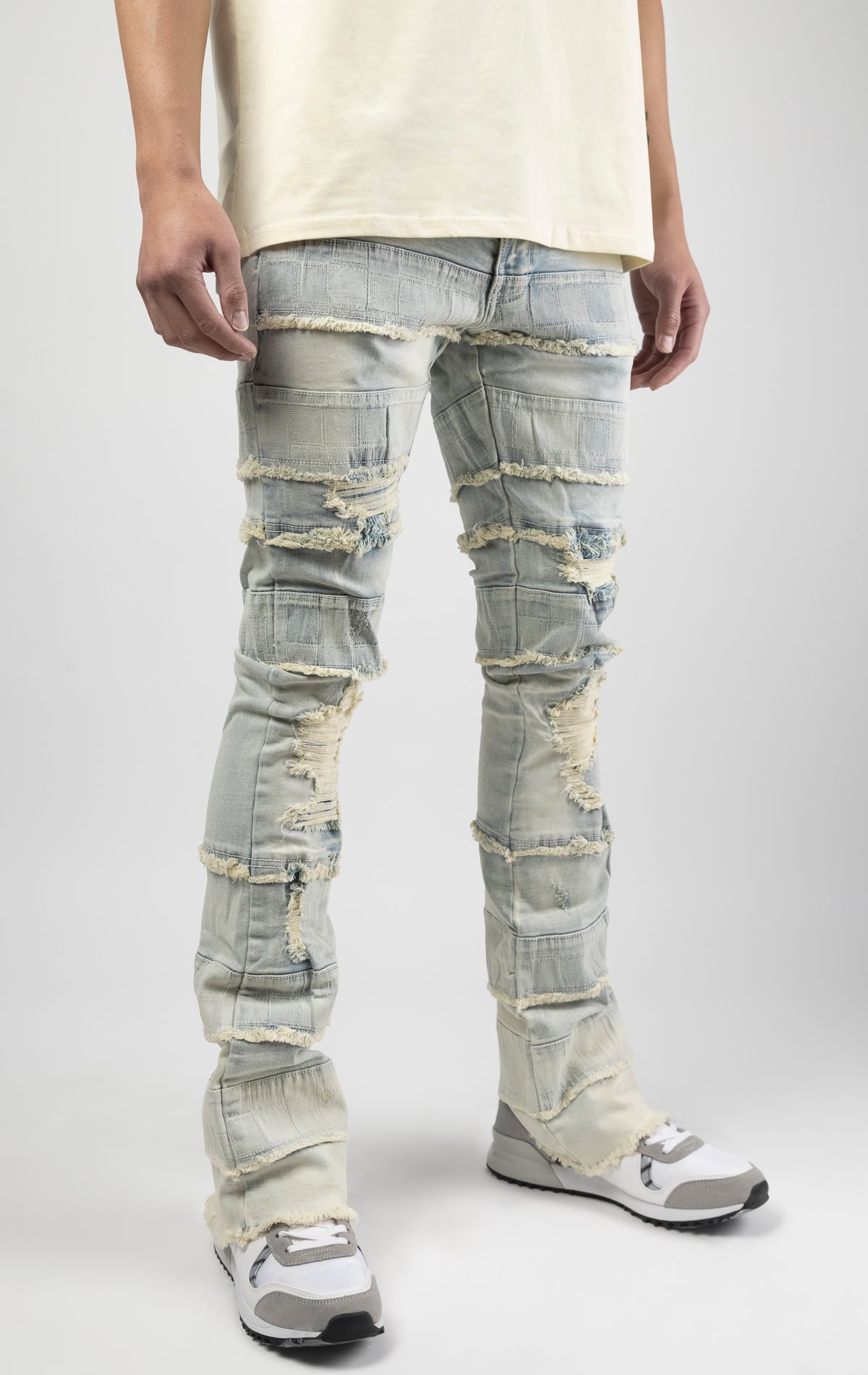 Light wash iconic stacked jeans crafted from high-quality, durable denim fabric consisting of 98% cotton and 2% spandex with a semi flare silhouette and a length of 35"-37". Featuring a distinctive ripped and repair design with pocket patches and a multi-tone dye throughout, these urban-inspired pants are true to size