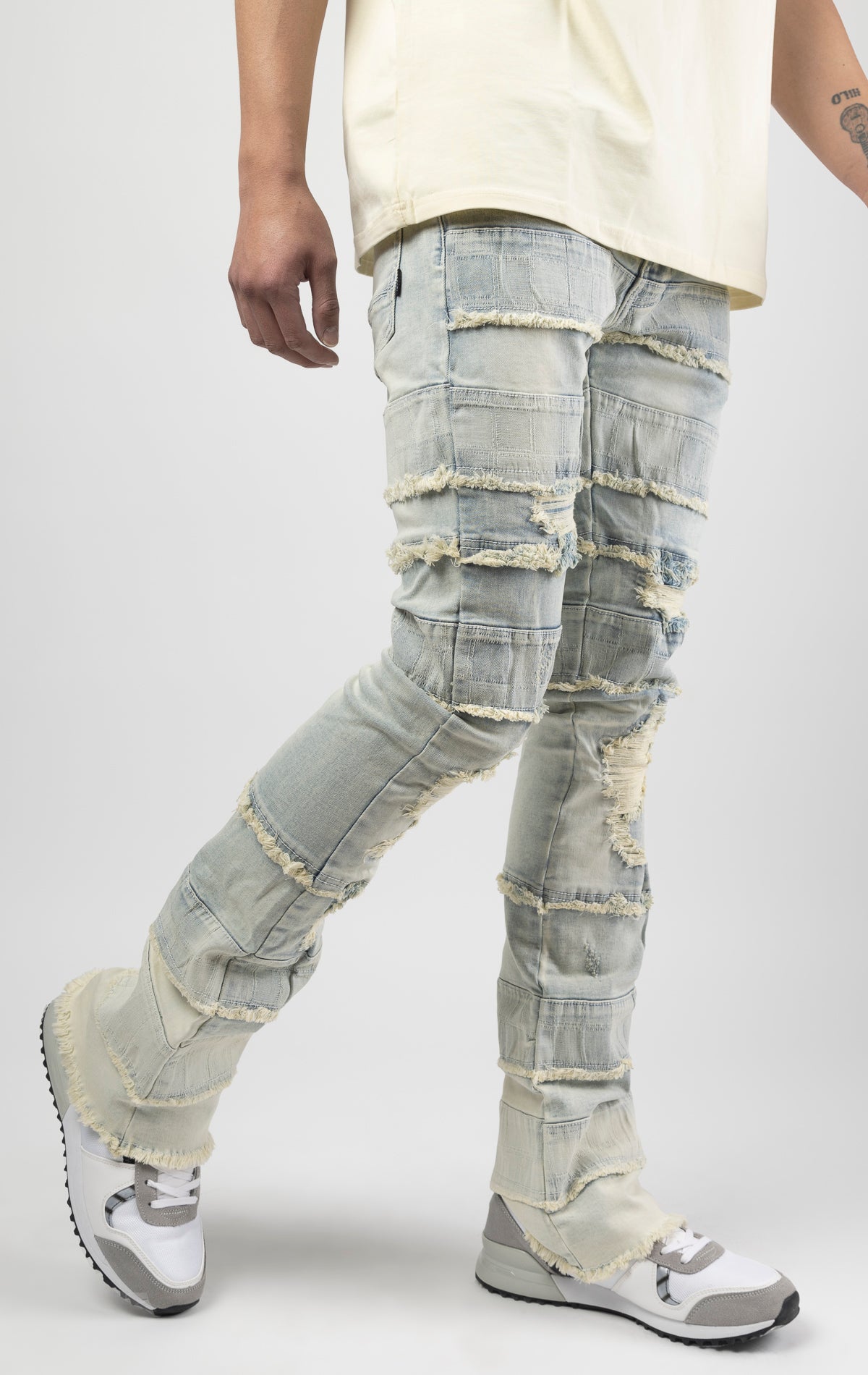 Light wash iconic stacked jeans crafted from high-quality, durable denim fabric consisting of 98% cotton and 2% spandex with a semi flare silhouette and a length of 35"-37". Featuring a distinctive ripped and repair design with pocket patches and a multi-tone dye throughout, these urban-inspired pants are true to size