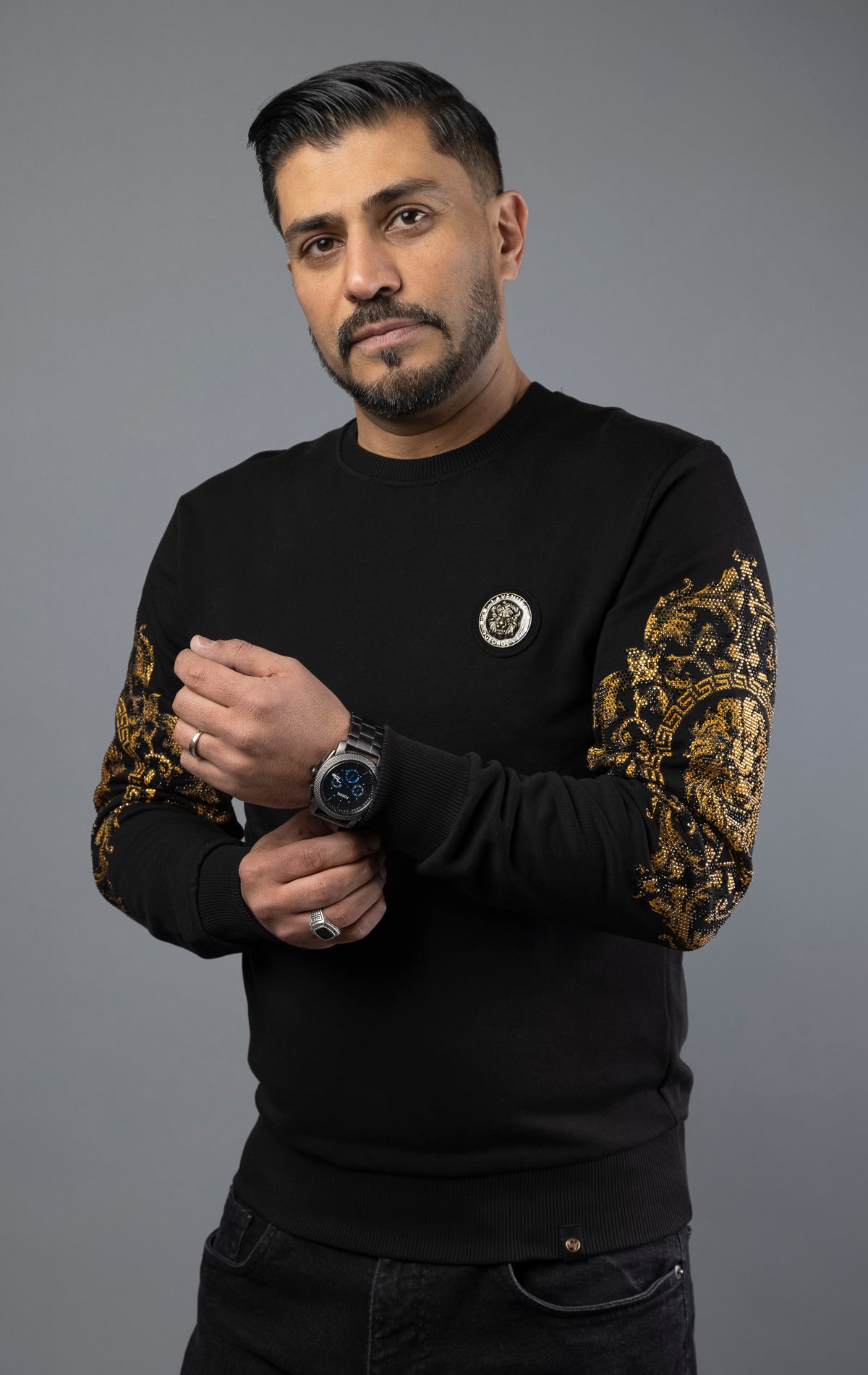 Black Soft and comfortable GV sweater with round-neck, long sleeves, and a Lion pin. The gold sleeves add a touch of elegance, making it suitable for daily wear. Made with soft cotton for ultimate comfort.