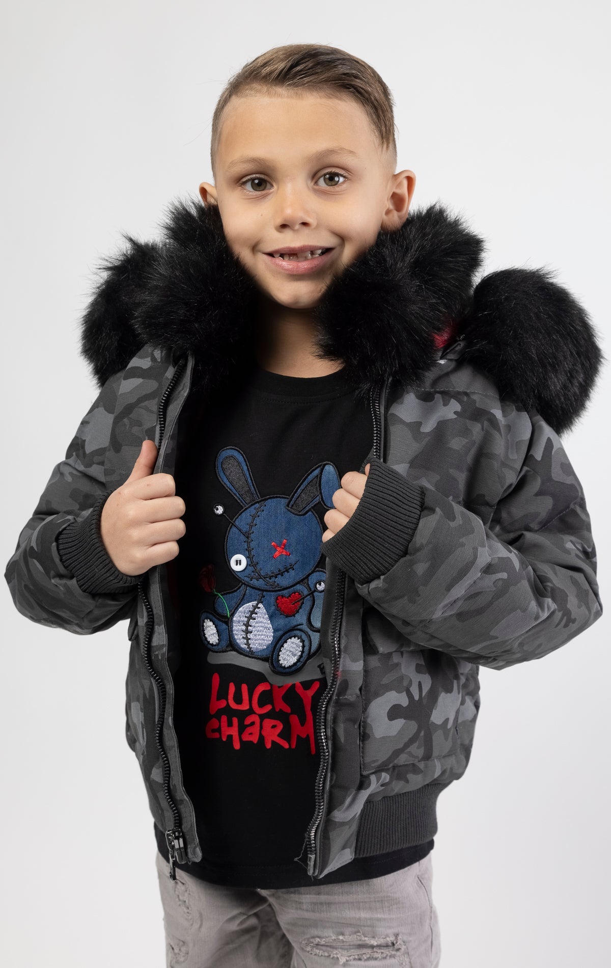 Full zip bomber jacket silhouette, with quilted padding and dense insulation for extreme warmth. Made with 100% polyester lining and featuring a removable faux jackal fur collar and hood. Available in woodland and black camo.