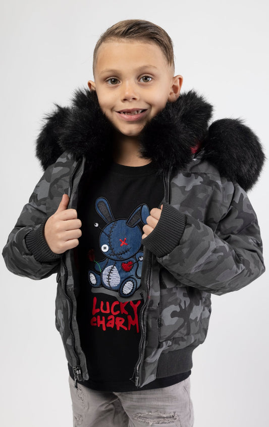 Full zip bomber jacket silhouette, with quilted padding and dense insulation for extreme warmth. Made with 100% polyester lining and featuring a removable faux jackal fur collar and hood. Available in woodland and black camo.