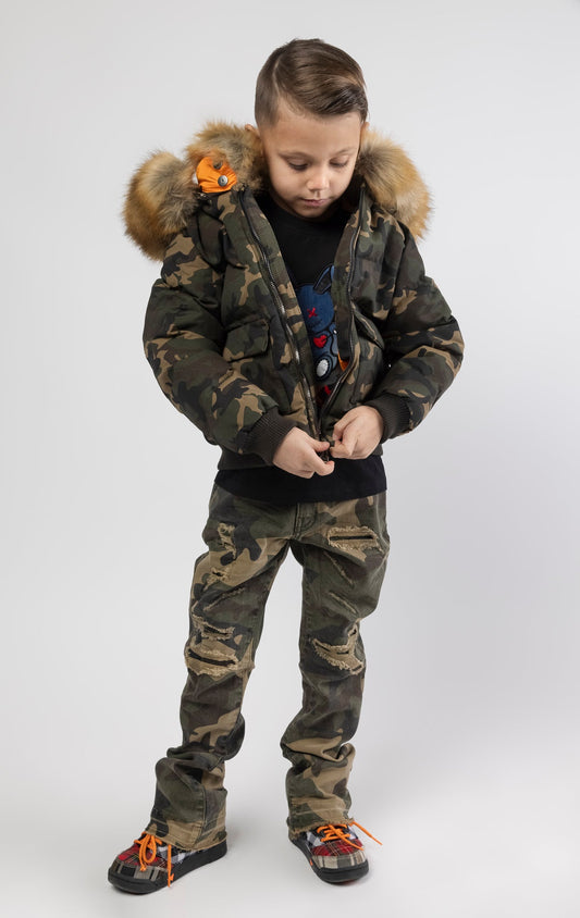 Full zip bomber jacket silhouette, with quilted padding and dense insulation for extreme warmth. Made with 100% polyester lining and featuring a removable faux jackal fur collar and hood. Available in woodland and black camo.