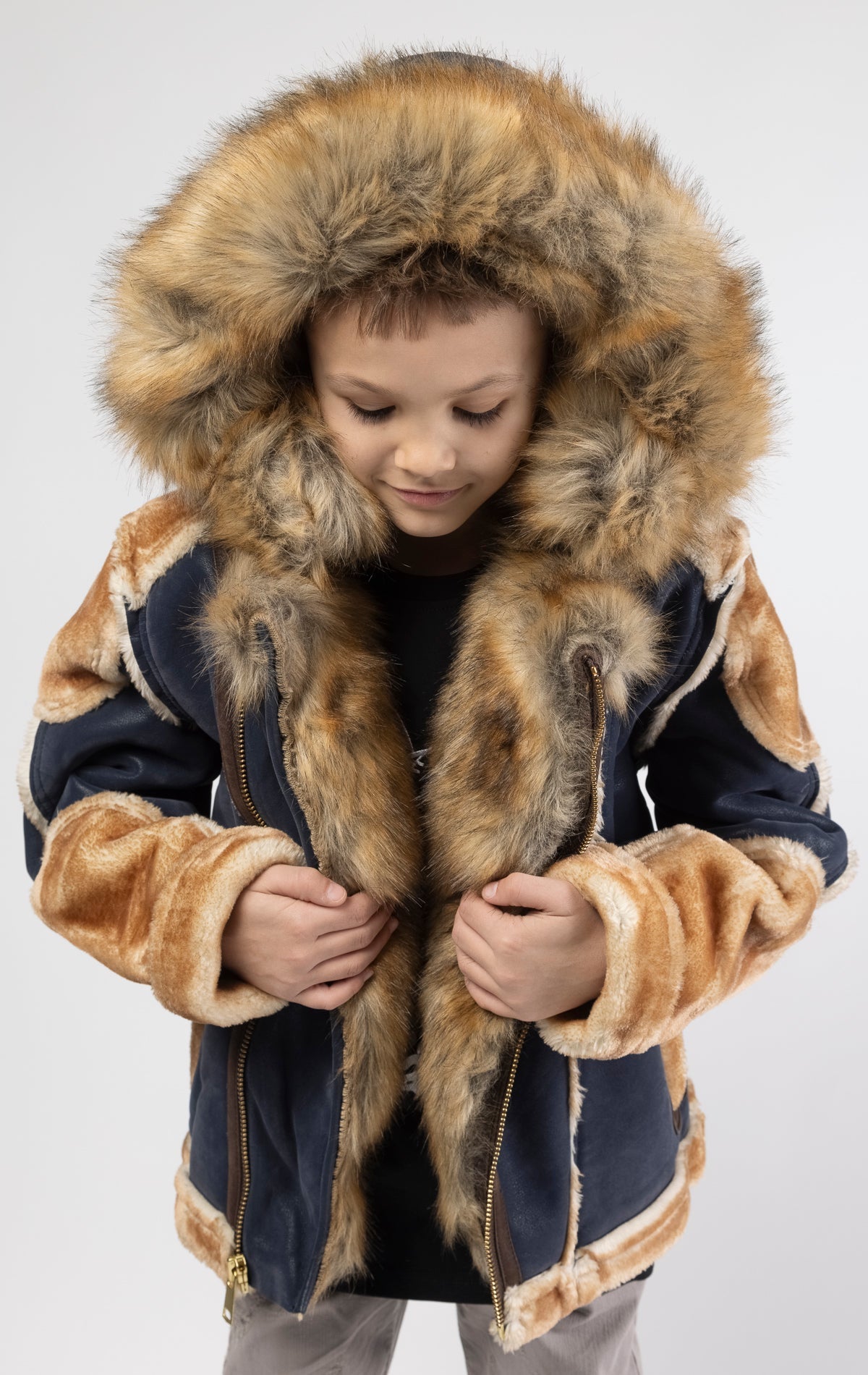 Faux suede body. Soft faux shearling lining on the body, sleeves, and pockets. Toggle front closure with vegan suede straps and a buckle at the neck. Detachable hood made of faux fox fur with a zipper.