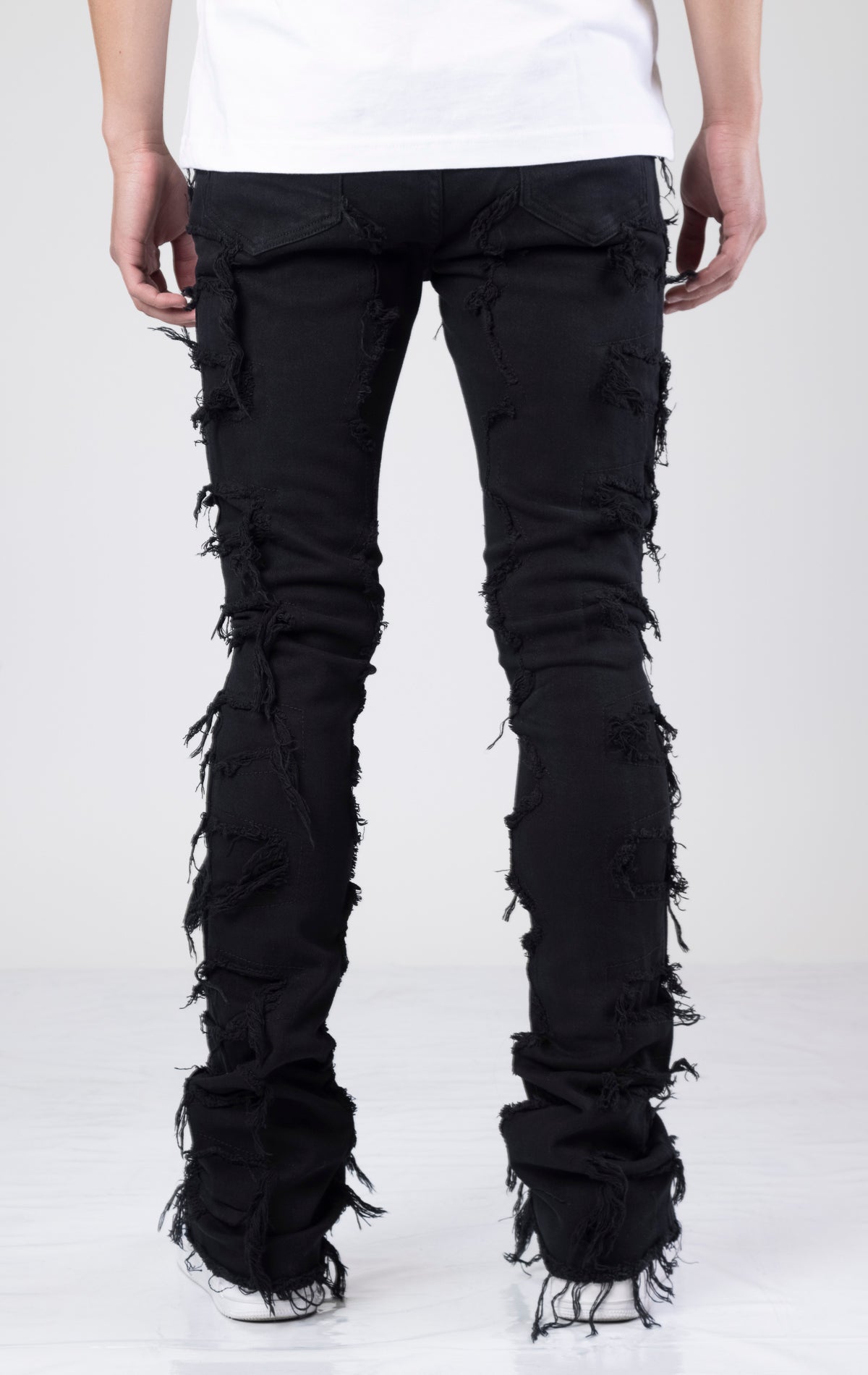 Black, tapered stacked jeans with frayed hems made of 98% cotton and 2% elastane.  Custom hardware and five pockets.