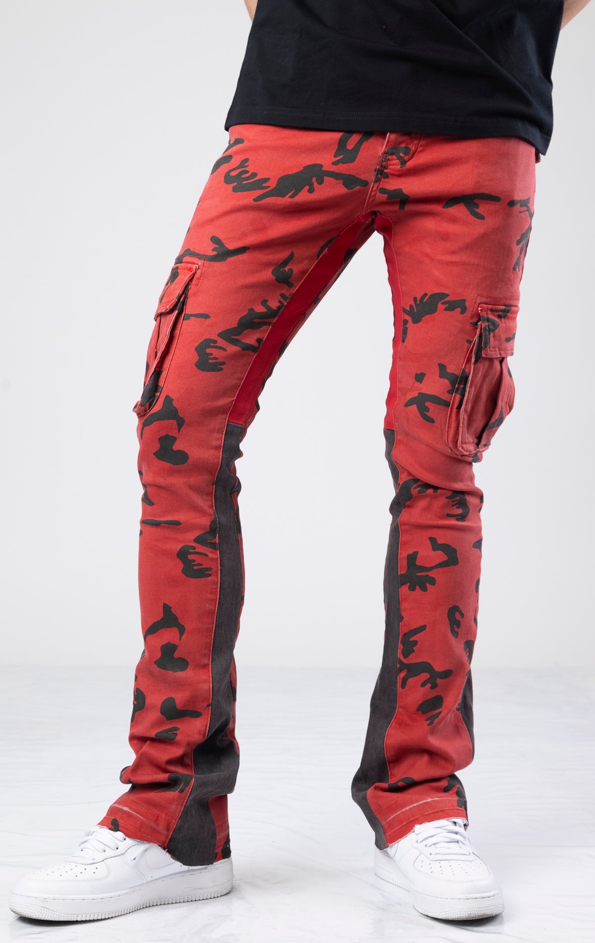 Red and black stacked flare denim jeans with a crimson forest all-over print. They have a contemporary, fitted silhouette that flares out from the knee. The jeans have multiple functional pockets with zipper details for closure and style. Made from a durable cotton blend with a touch of elastane for stretch and comfort, these jeans also include belt loops for added adjustability.