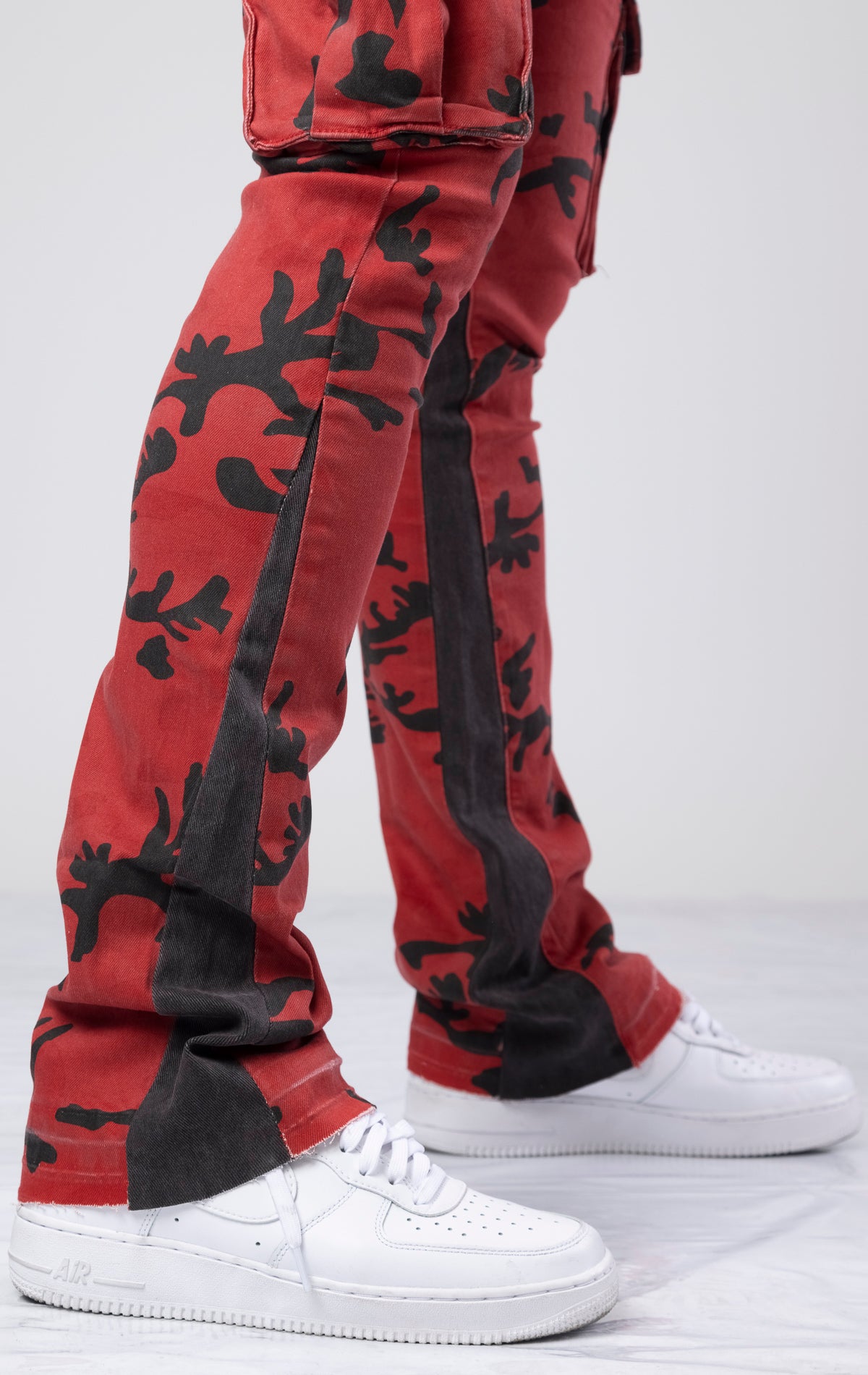 Red and black stacked flare denim jeans with a crimson forest all-over print. They have a contemporary, fitted silhouette that flares out from the knee. The jeans have multiple functional pockets with zipper details for closure and style. Made from a durable cotton blend with a touch of elastane for stretch and comfort, these jeans also include belt loops for added adjustability.