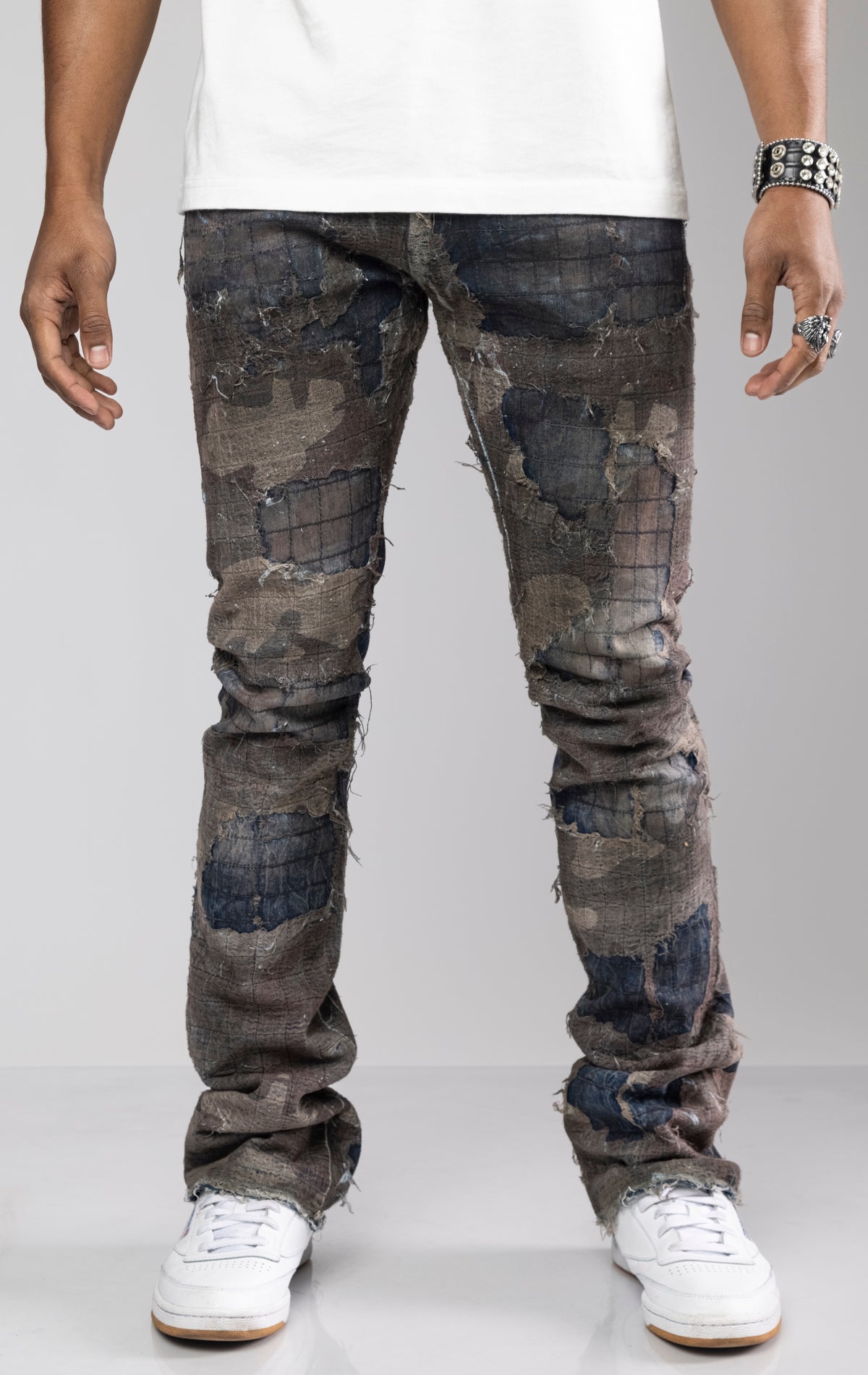 Distressed skinny flare jeans with stacked ankles. Jeans feature all-over gauze patches, intricate stitching, and a ripped and repaired aesthetic. share more_vert