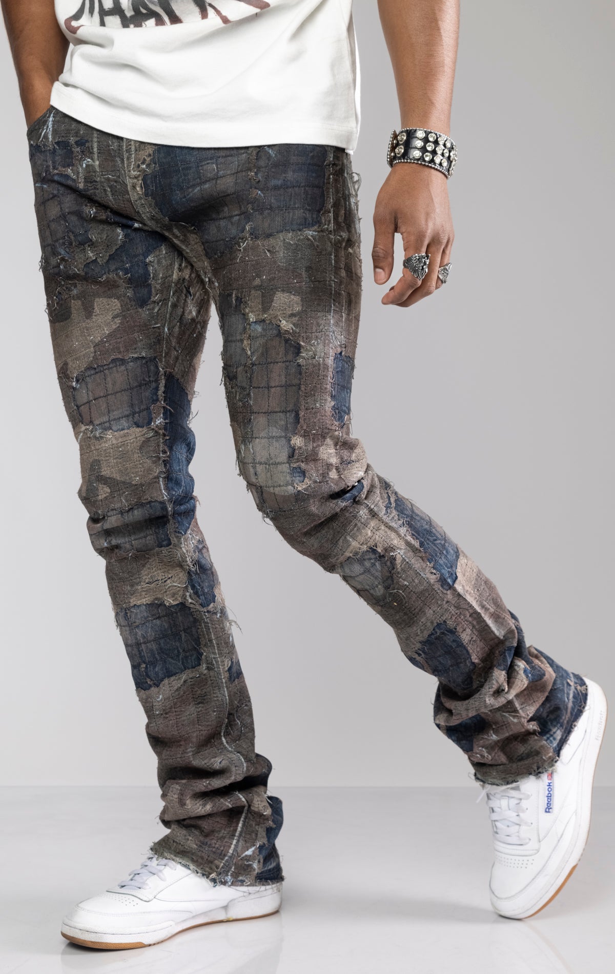 Distressed skinny flare jeans with stacked ankles. Jeans feature all-over gauze patches, intricate stitching, and a ripped and repaired aesthetic. share more_vert