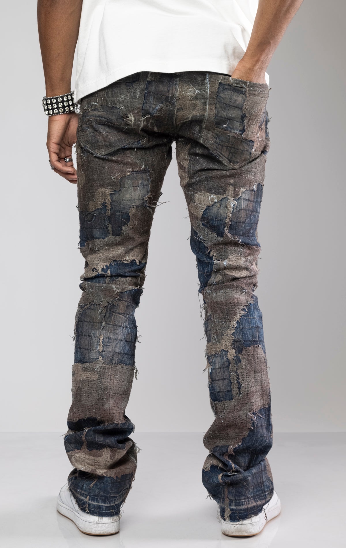 Distressed skinny flare jeans with stacked ankles. Jeans feature all-over gauze patches, intricate stitching, and a ripped and repaired aesthetic. share more_vert