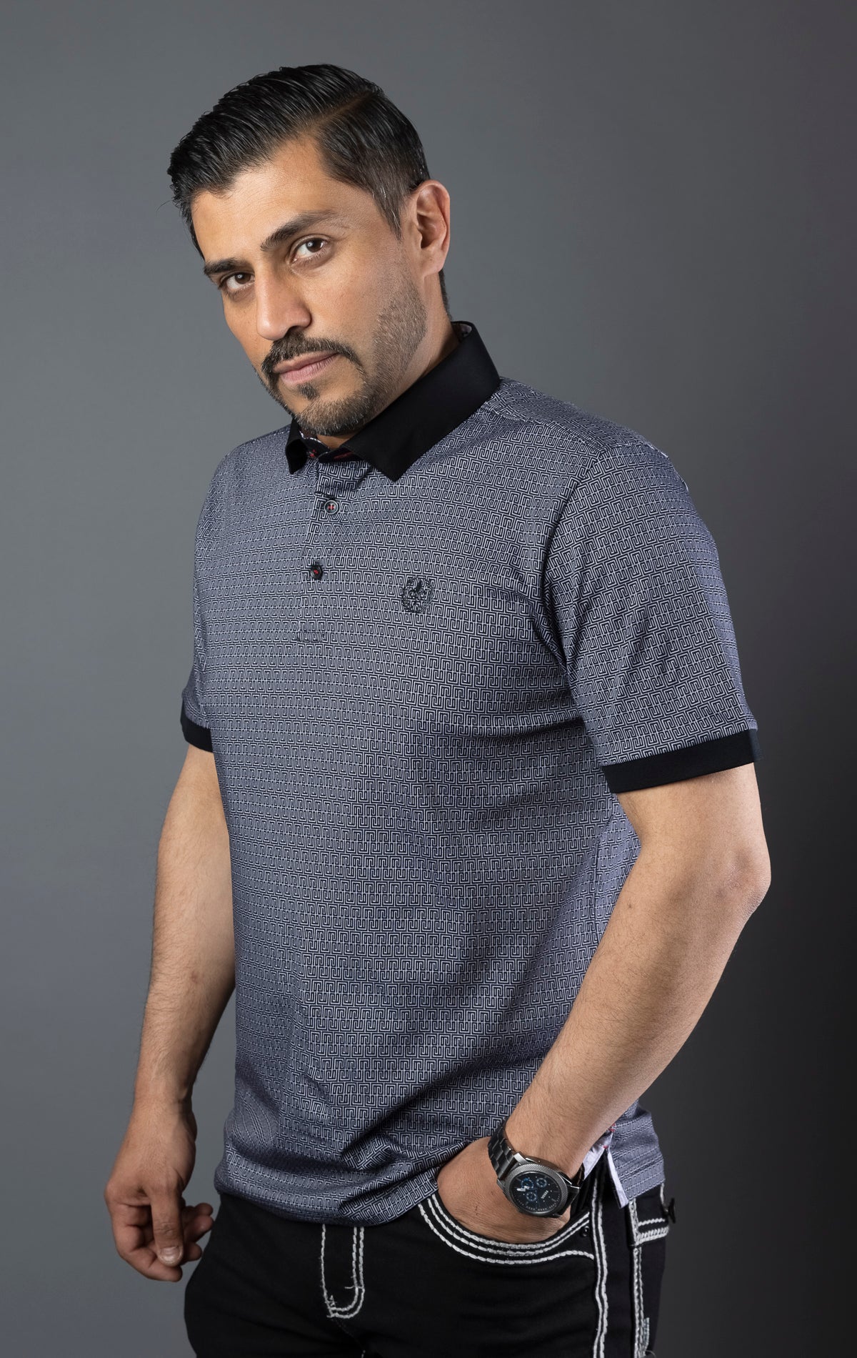 Male model wearing black semi-fitted polo shirt with a contrasting collar. The polo is made from light-colored, breathable knit fabric.