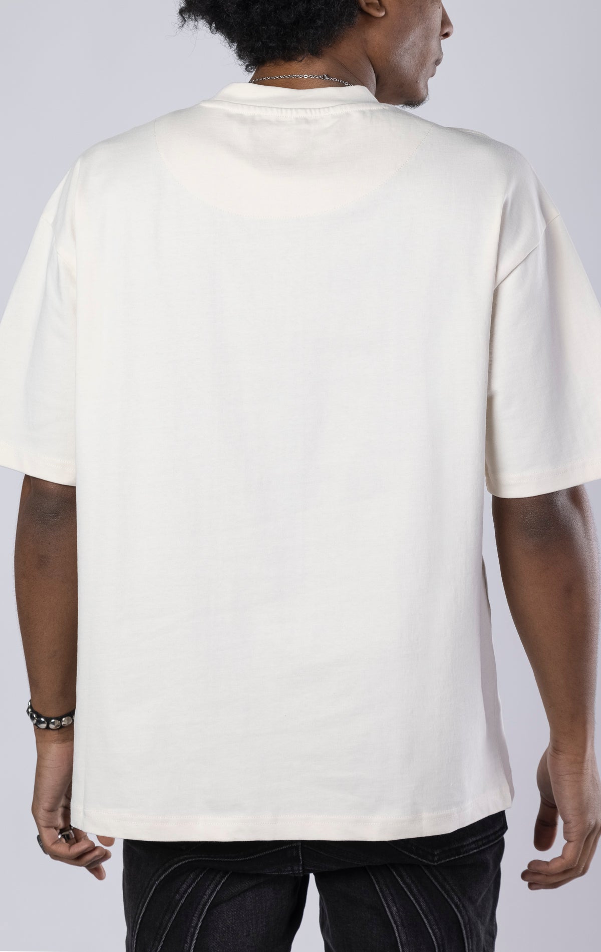 Blessed Darkness Boxy Tee. Cream t-shirt made from 100%  250gr cotton. Features a boxy fit, dropped shoulders, longer sleeves, a 3D embroidered front message, and subtle "blessed" branding