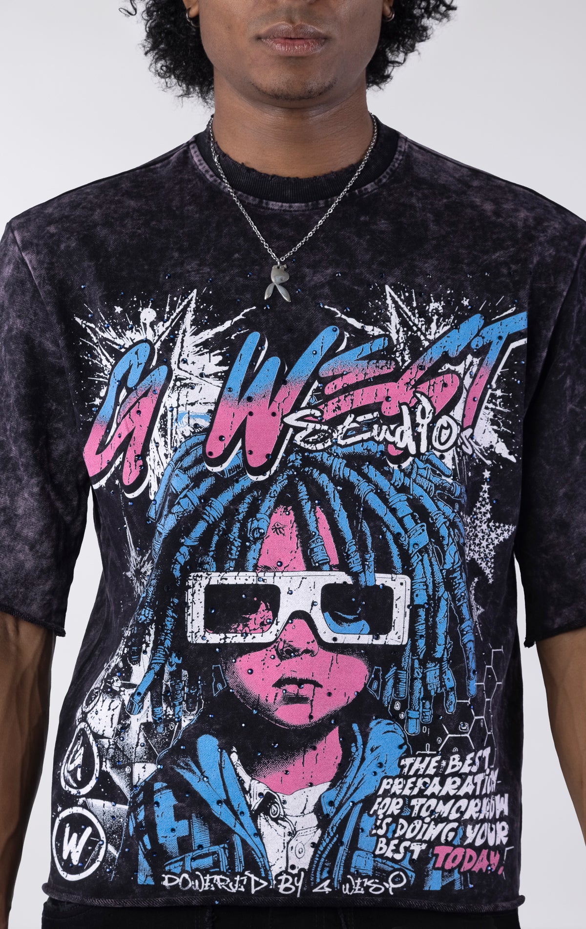 Washed black/purple oversized t-shirt featuring a large graphic of a figure with blue dreadlocks and white 3D glasses. The graphic includes the text "G-WEST Studios" and "THE BEST PREPARATION FOR TOMORROW IS DOING YOUR BEST TODAY!" accented with rhinestones.