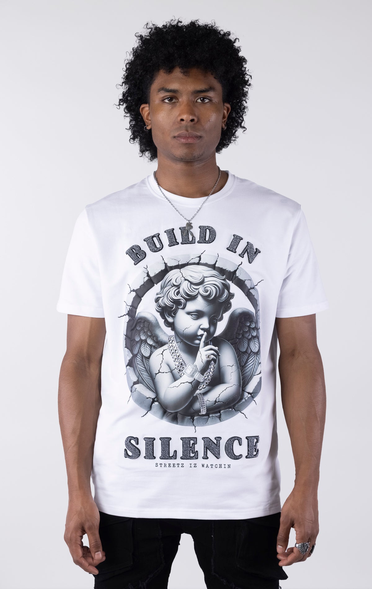 White t-shirt with a large graphic of a monochromatic cherub statue wearing chains and holding a finger to its lips. The graphic is surrounded by cracked stone and the text 