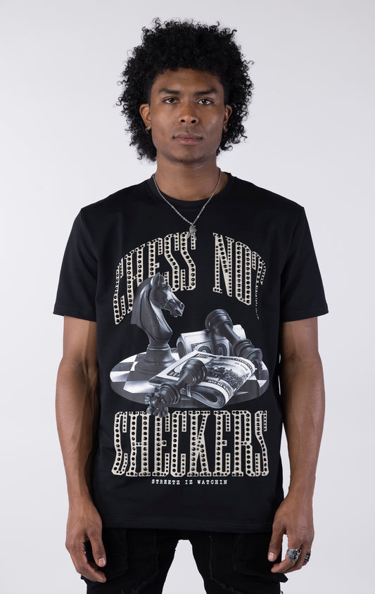Black t-shirt with a large graphic featuring a black chess knight, fallen pawns, and stacks of money on a checkered surface. The text "CHESS NOT" and "CHECKERS" is printed above and below the graphic in a sparkling white-outlined font.