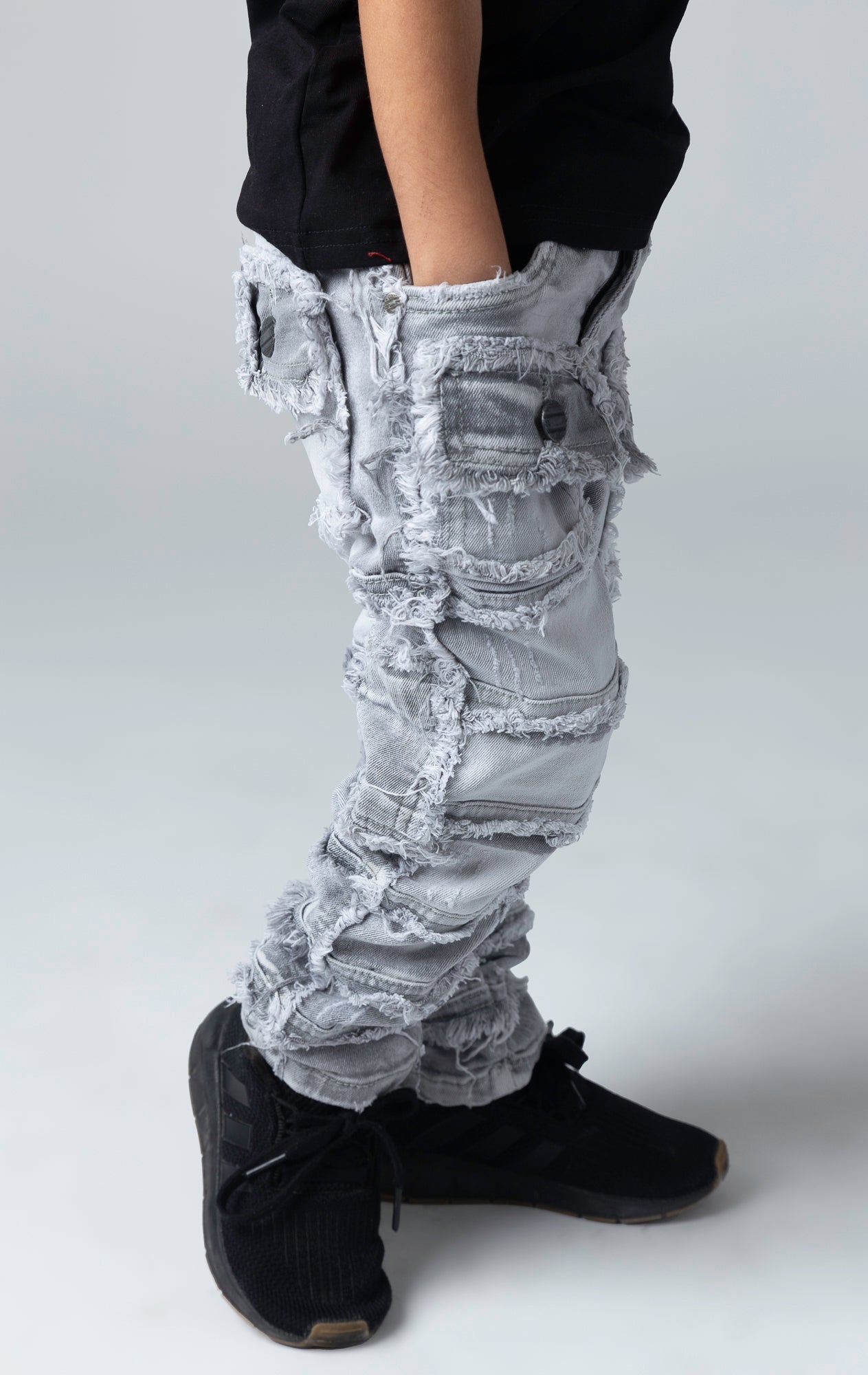 Stretch stacked denim pants for kids, distressed and paneled with a raw finishing 