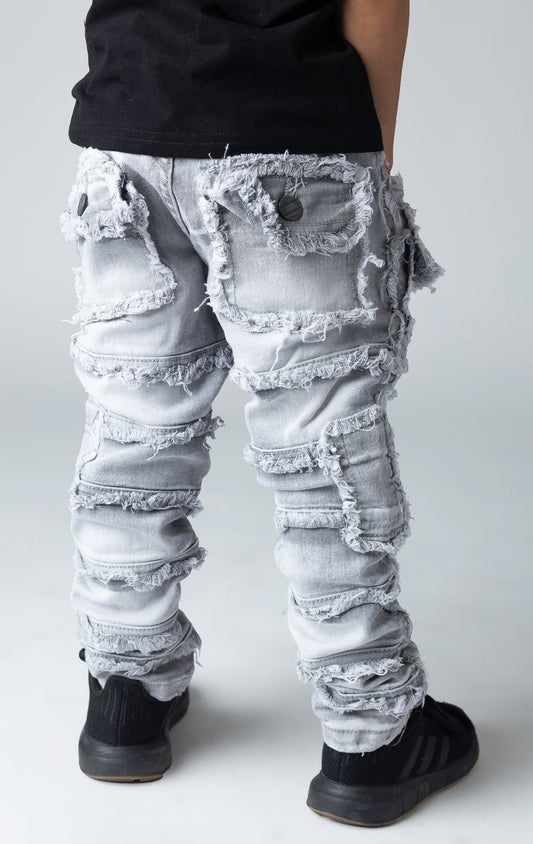 Stretch stacked denim pants for kids, distressed and paneled with a raw finishing 