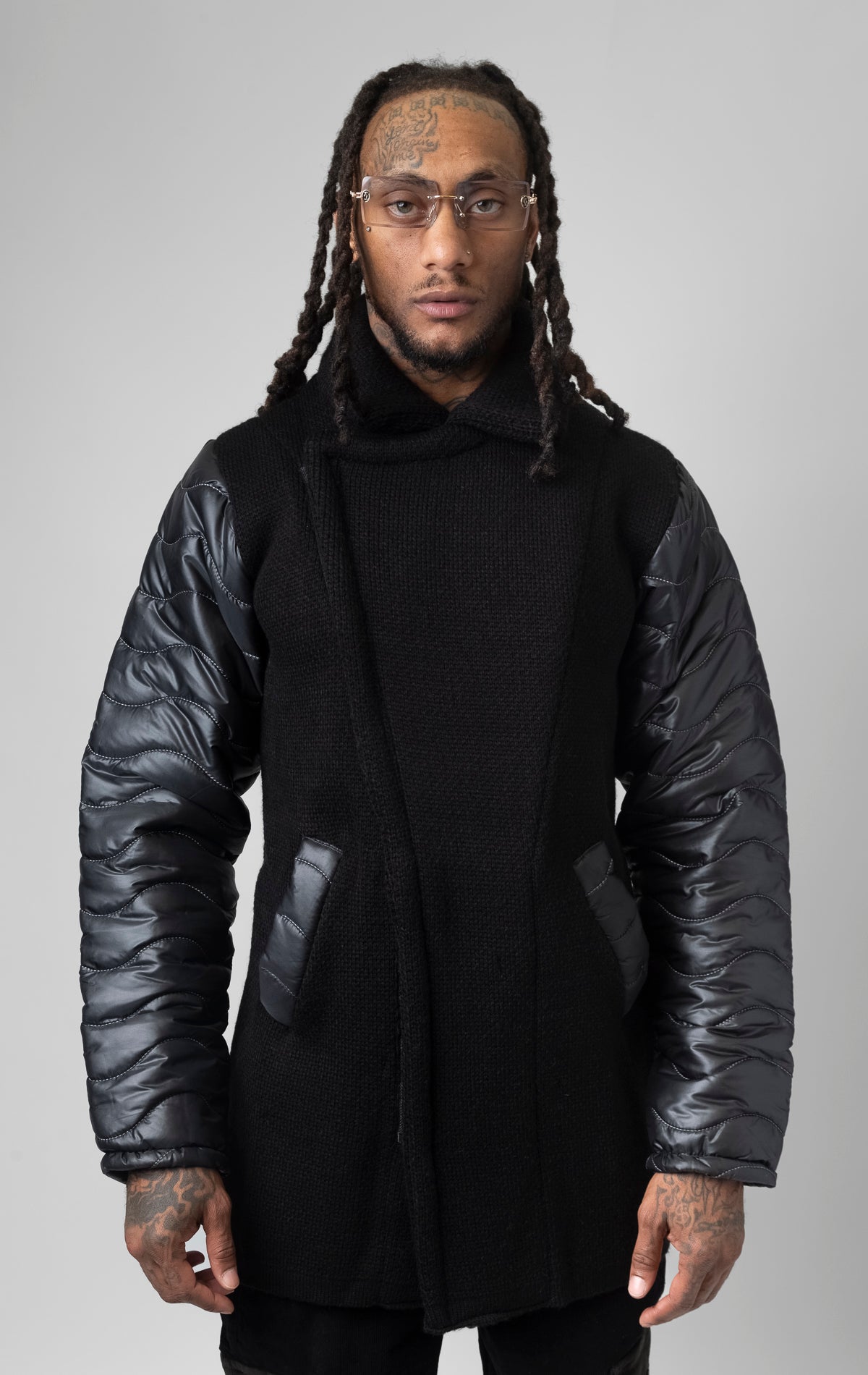 black coat made of contrasting fabrics, with a wool front and puffer sleeves.