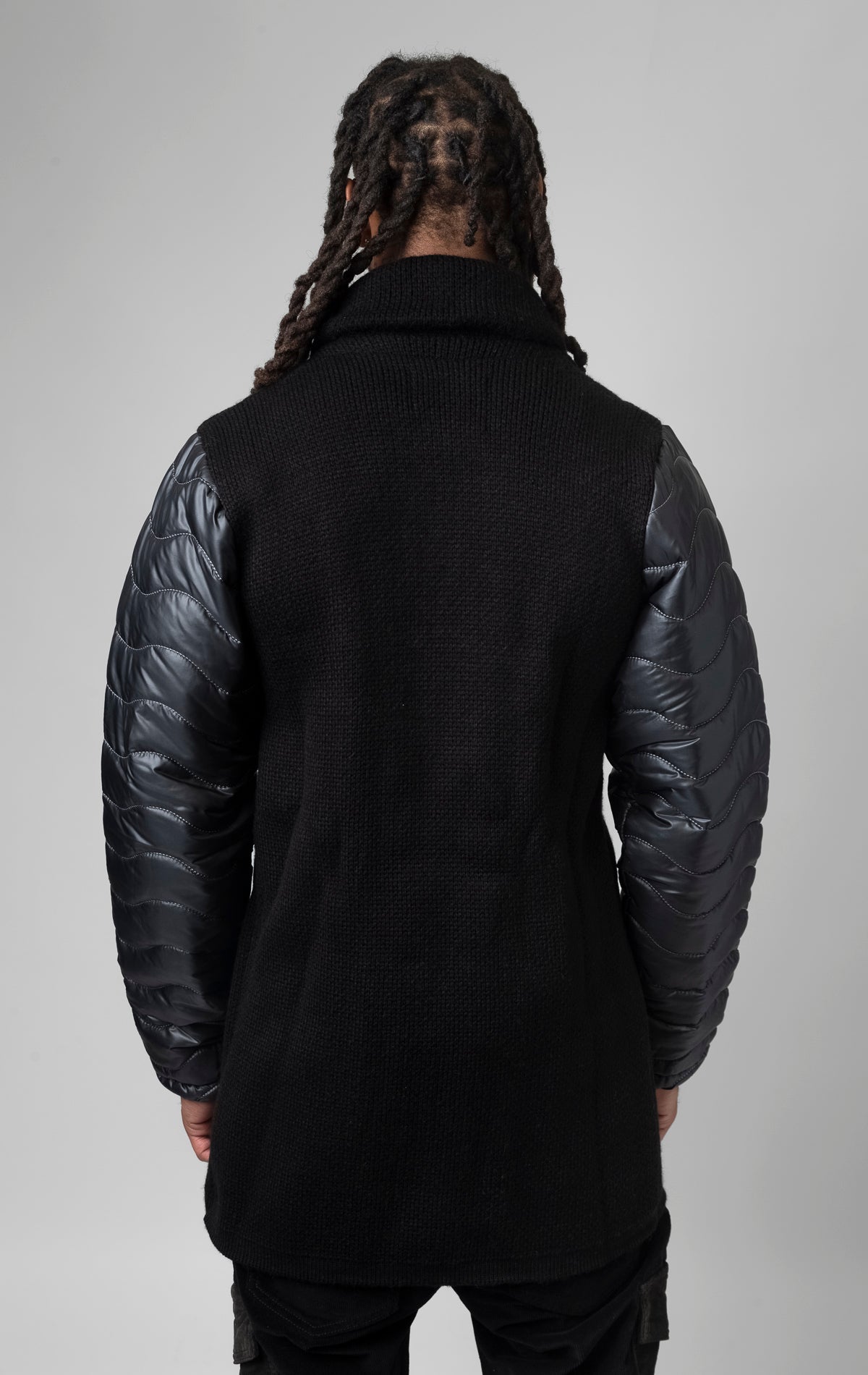 black coat made of contrasting fabrics, with a wool front and puffer sleeves.