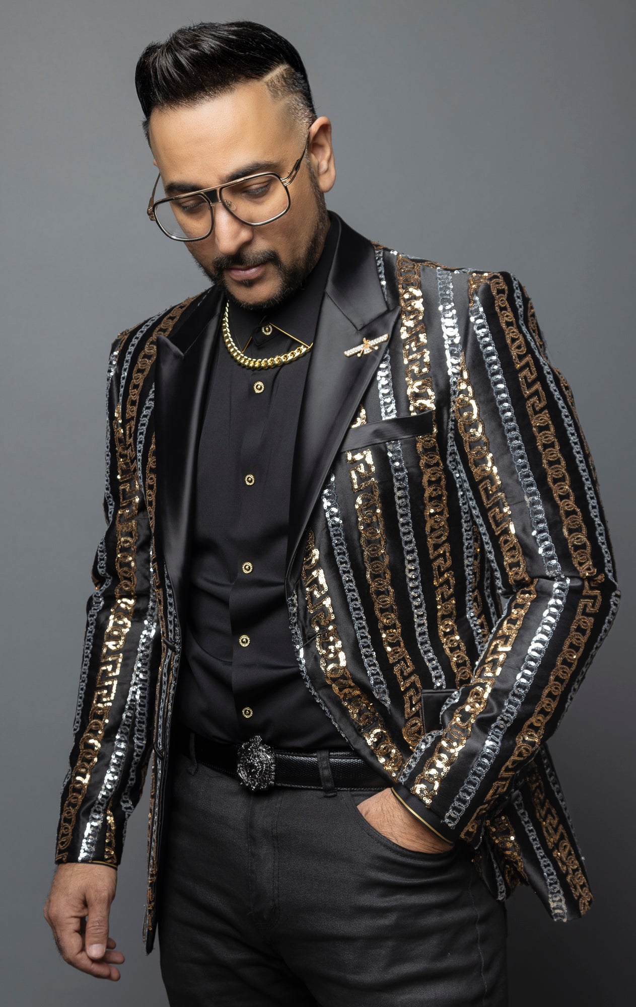 Men's slim-fit blazer with a satin notch lapel, long sleeves, and two-button closure. The blazer features a unique pattern combining Cuban chain, Greek key, and sequin designs.  Made from 100% regenerated fiber. 