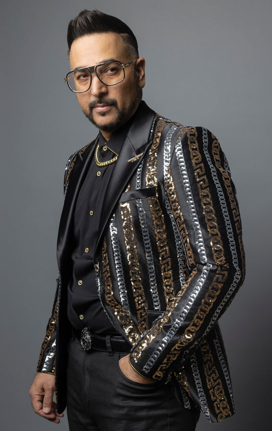 Men's slim-fit blazer with a satin notch lapel, long sleeves, and two-button closure. The blazer features a unique pattern combining Cuban chain, Greek key, and sequin designs. Made from 100% regenerated fiber.