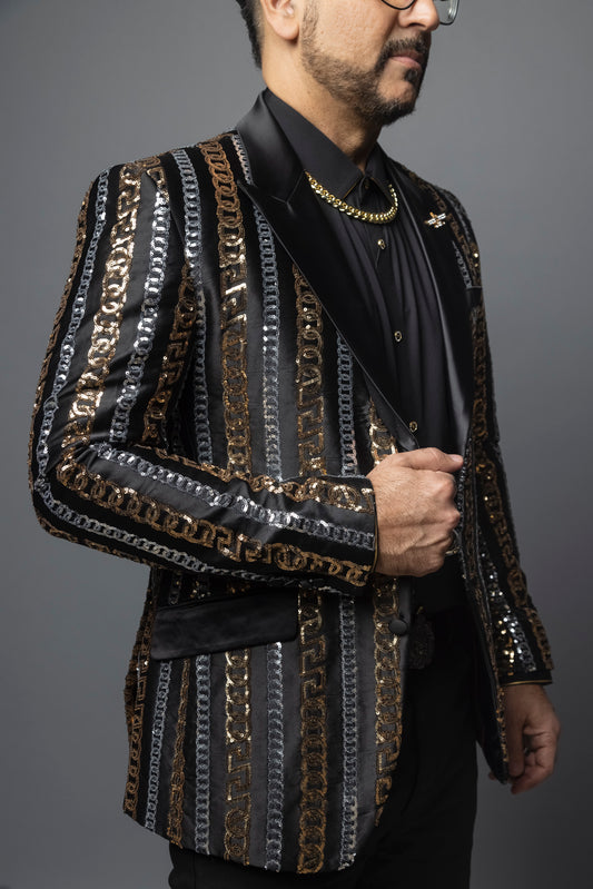 Men's slim-fit blazer with a satin notch lapel, long sleeves, and two-button closure. The blazer features a unique pattern combining Cuban chain, Greek key, and sequin designs. Made from 100% regenerated fiber.
