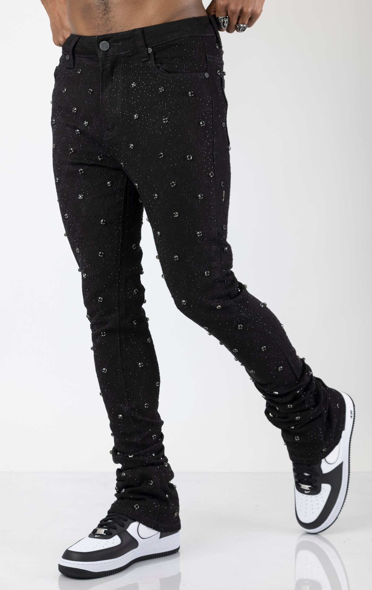 Men's black, tapered-fit jeans with a luxurious cotton-blend fabric (98% cotton, 2% elastane) and custom hardware. The jeans feature subtle laser distressing throughout, delicate diamond embellishments, and a five-pocket design. They stack comfortably above the ankle.