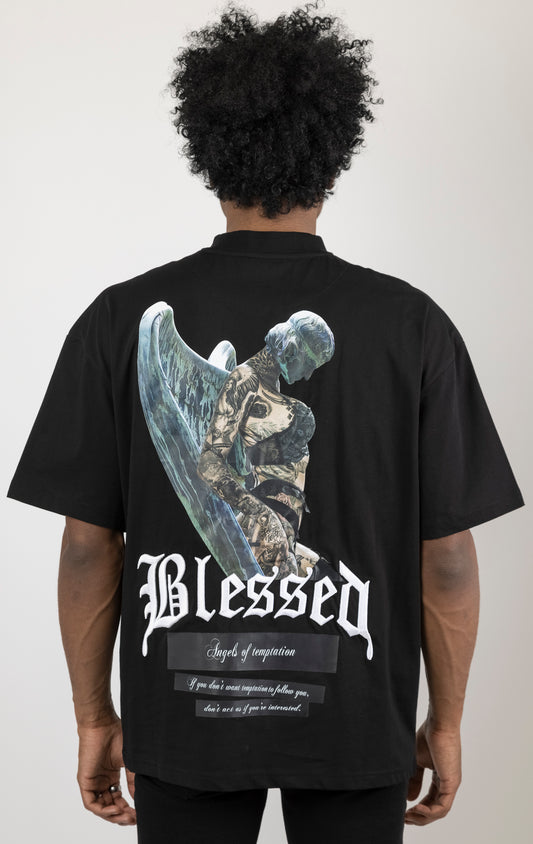 Men's boxy fit t-shirt in black. The shirt features dropped shoulders, longer sleeves, and a wide, fitted neck rib. It has "Angels of Temptation" printed on the front and back with 3D "blessed" embroidery on the chest and back. Made from 100% cotton jersey (190gsm). A "blessed" slogan is printed on the inner neck binding.