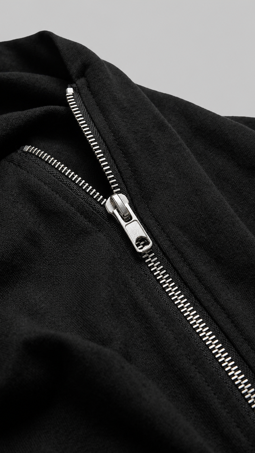 Close-up of a black shirt with a silver zipper on a grey background