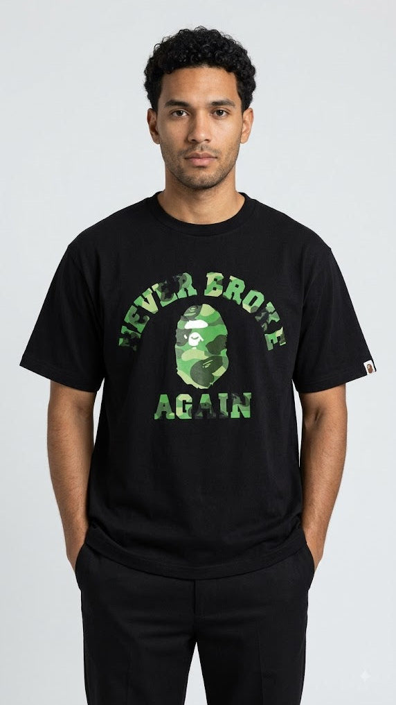 A man wearing a black short-sleeve t-shirt with a green camouflage graphic of the A Bathing Ape head and the text 'NEVER BROTE AGAIN' in green, paired with black pants, against a light gray studio background.