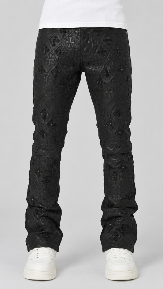 Black textured jeans with an allover embossed geometric pattern, shown on a model from the waist down wearing white sneakers against a light gray studio background.