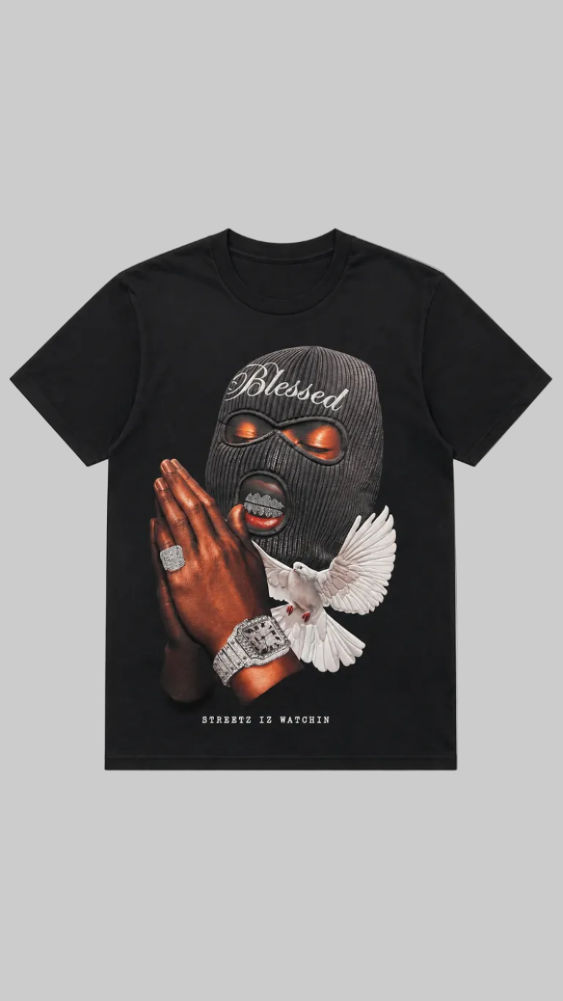 A black short-sleeve graphic t-shirt featuring a front print of a person in a black ski mask with 'Blessed' written on it, praying hands with rings, a white dove, and the text 'STREETZ IZ WATCHIN' at the bottom.