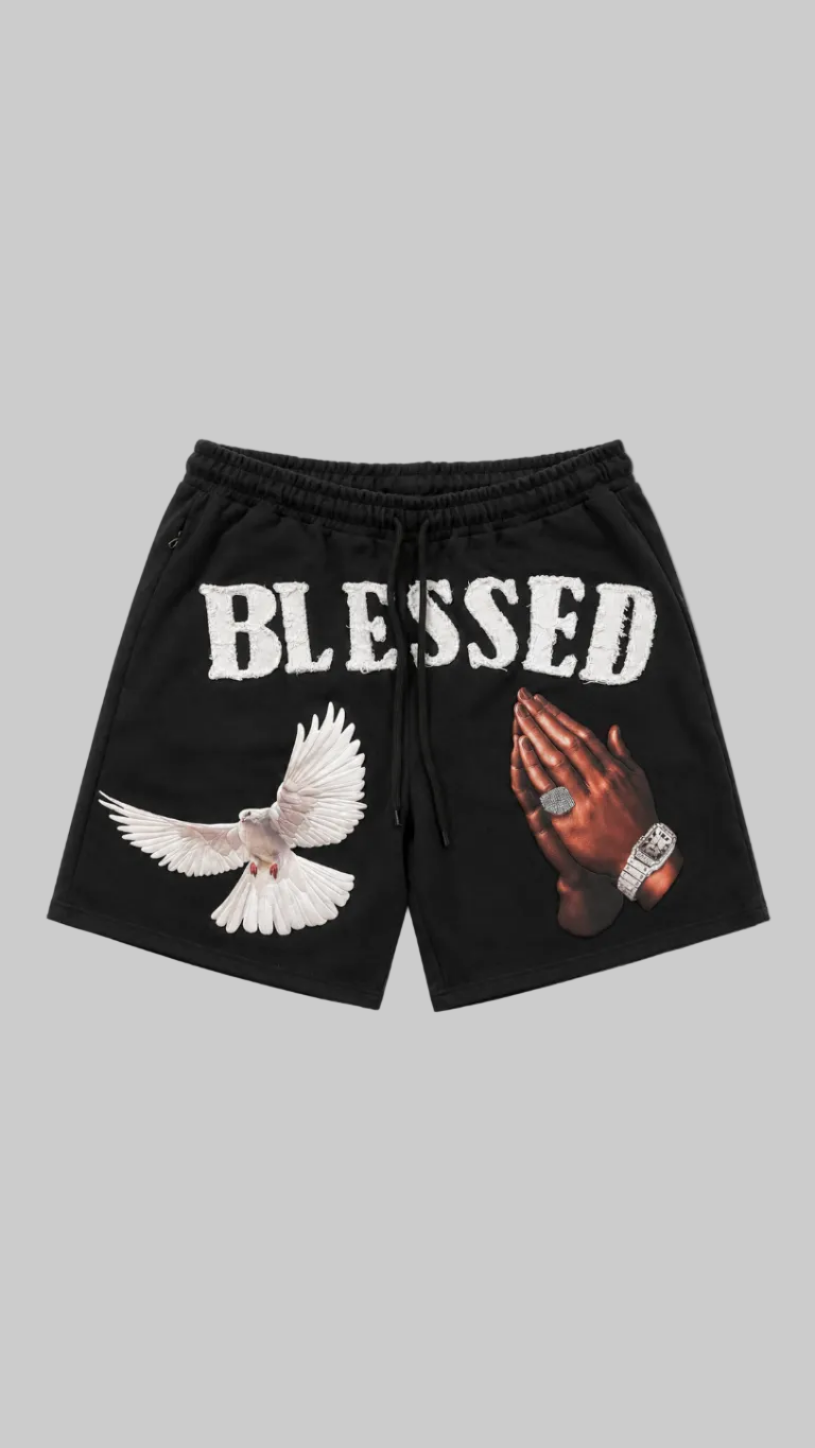 Black drawstring shorts with a white 'BLESSED' text print, a white dove graphic, and a praying hand graphic on a light gray background.