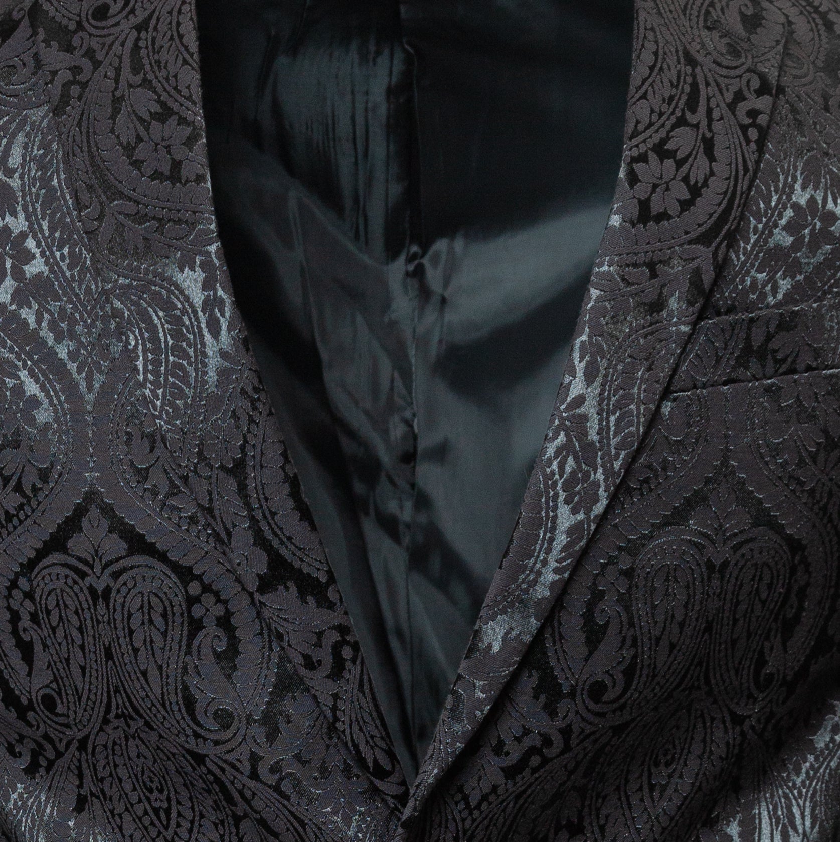 Men's slim-fit blazer in black. The blazer features a paisley patterned poly fabric, peak lapels, one-button closure, and double side vents. 