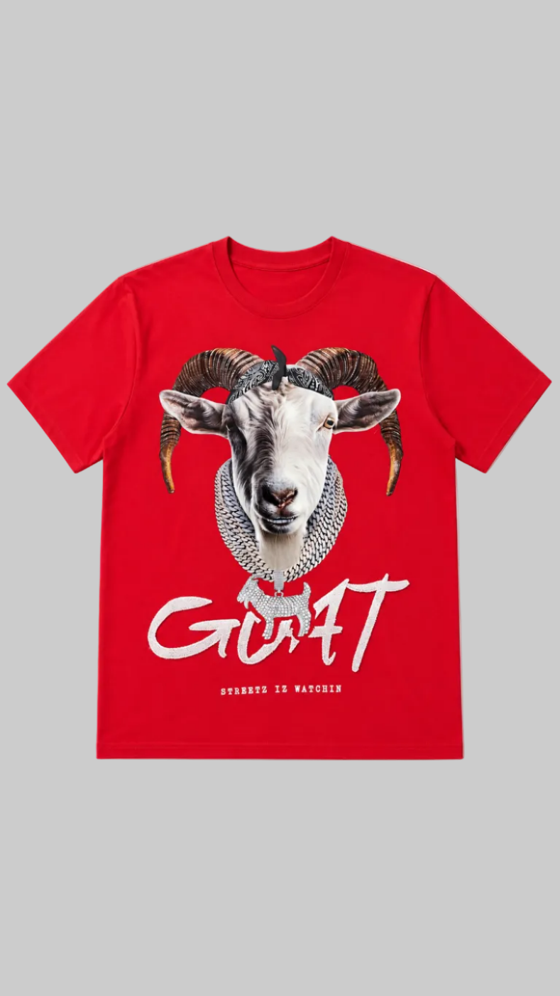 A bright red short-sleeve t-shirt featuring a large graphic print of a white goat head with curved brown horns, wearing a silver chain necklace. Below the graphic, the word 'GIAFT' is printed in a stylized white font, with 'GIAFT IS WAGENHEID' in smaller text underneath, all on a light gray background.