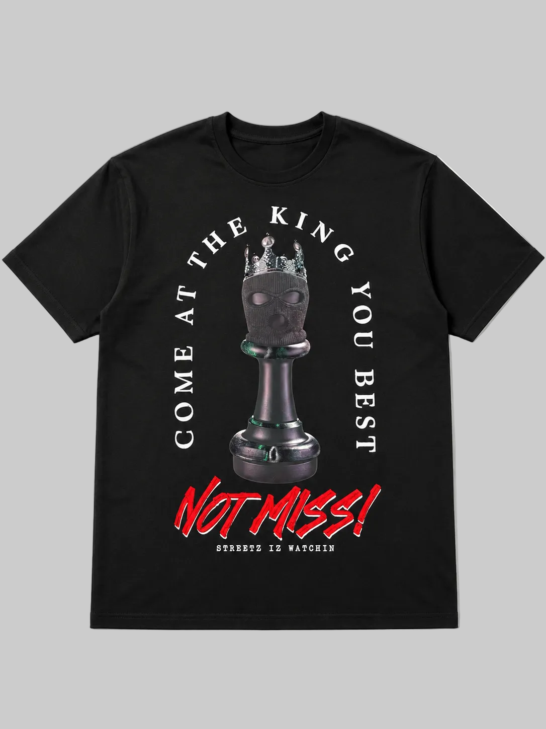 A black short-sleeve crewneck t-shirt featuring a graphic print of a chess king piece with a crown on its head. The text 'COME AT THE KING YOU BEST' is printed in white arching above the chess piece, and 'NOT MISS!' is printed in a bold red graffiti-style font below.