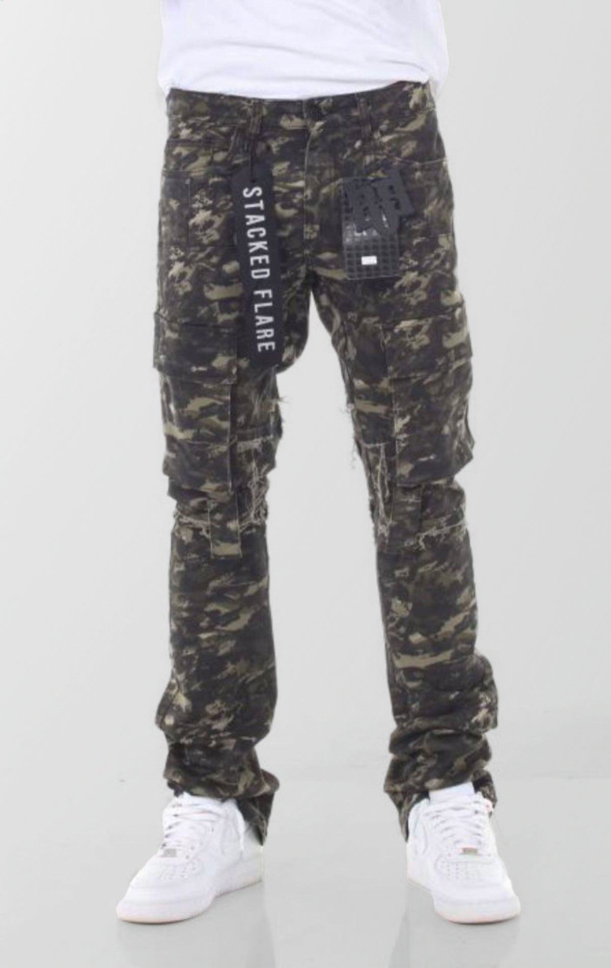 A pair of forest camouflage denim jeans featuring a slim fit that flares and stacks at the ankles, with distressed knees and multiple cargo pockets.