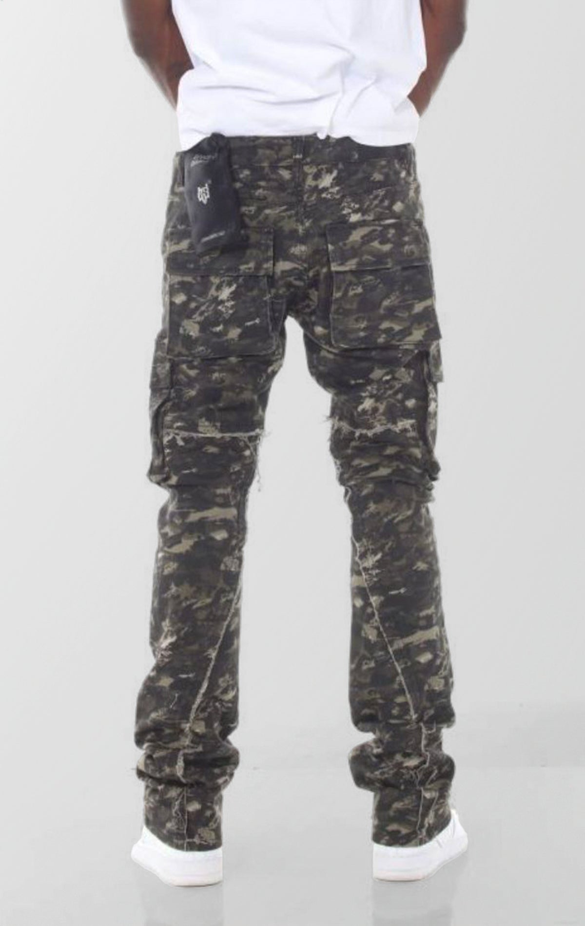 A pair of forest camouflage denim jeans featuring a slim fit that flares and stacks at the ankles, with distressed knees and multiple cargo pockets.