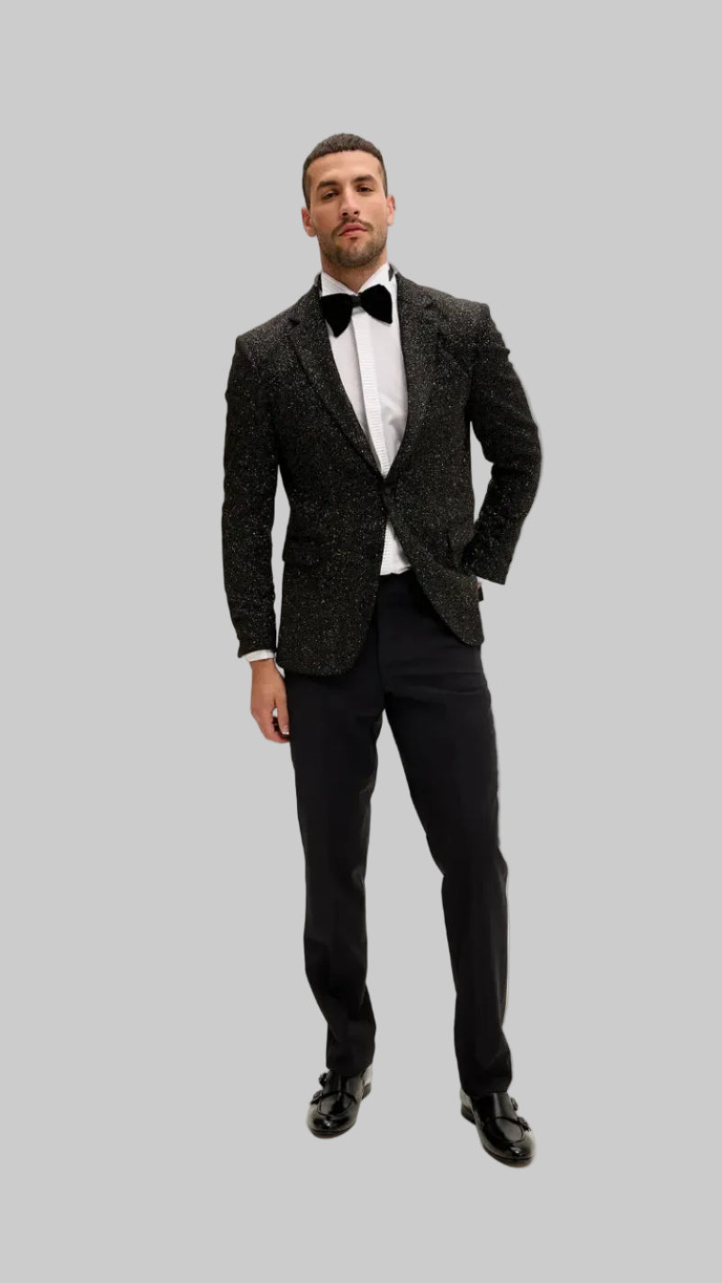 Man wearing a dark tuxedo with a white shirt and bow tie on a white background