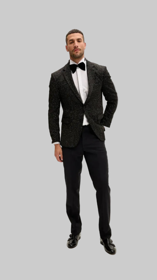 Man wearing a dark tuxedo with a white shirt and bow tie on a white background