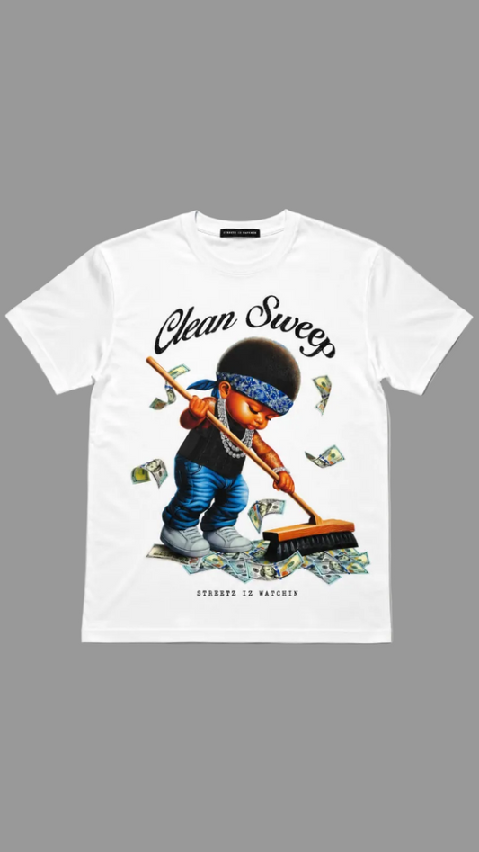 A white short-sleeve graphic T-shirt laid flat against a neutral gray background. The shirt features a large front print of a cartoon character sweeping money with a broom, with the words 'Clean Sweep' 