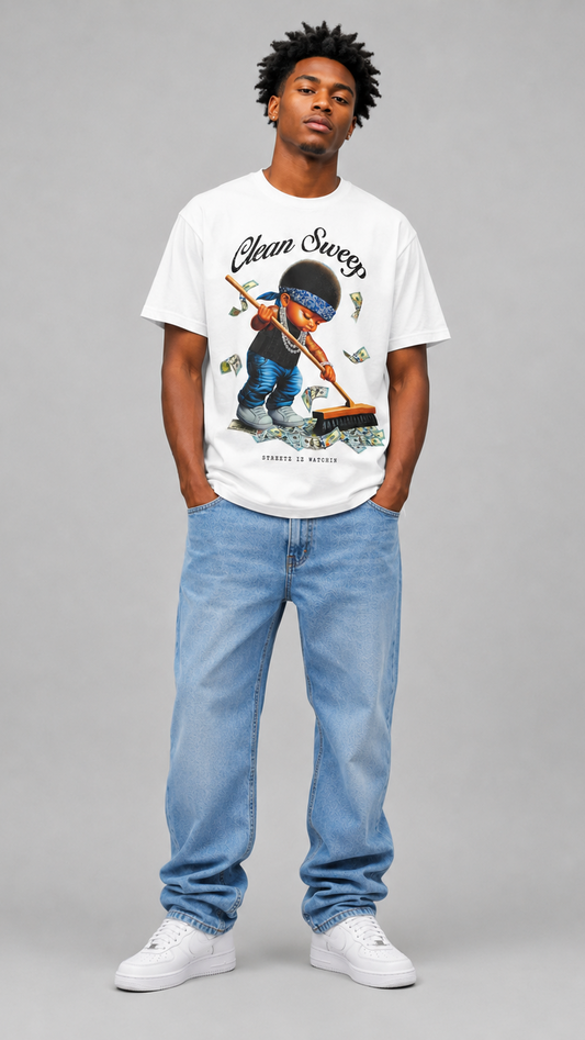 A man modeling a white graphic t-shirt with a 'Clean Sweep' design, paired with light blue jeans and white sneakers, standing against a solid gray studio background.