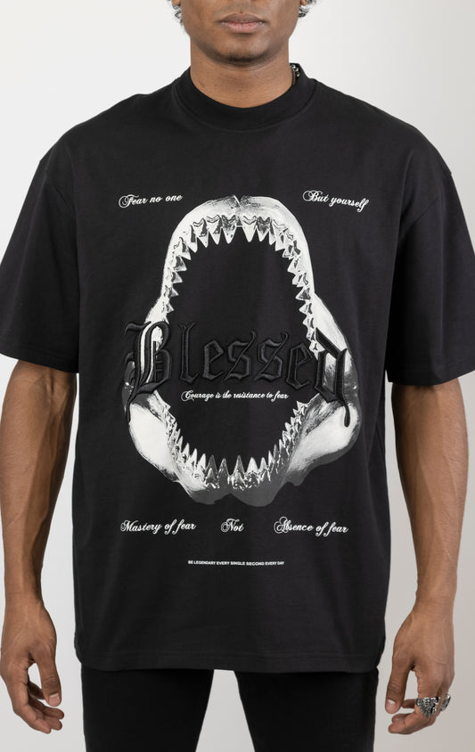 Men's boxy fit t-shirt in black. The shirt features dropped shoulders, longer sleeves, and a wide, fitted neck rib. It has a "Courage" front print with 3D embroidery. Made from 100% cotton jersey (190gsm). A "blessed" slogan is printed on the inner neck binding.