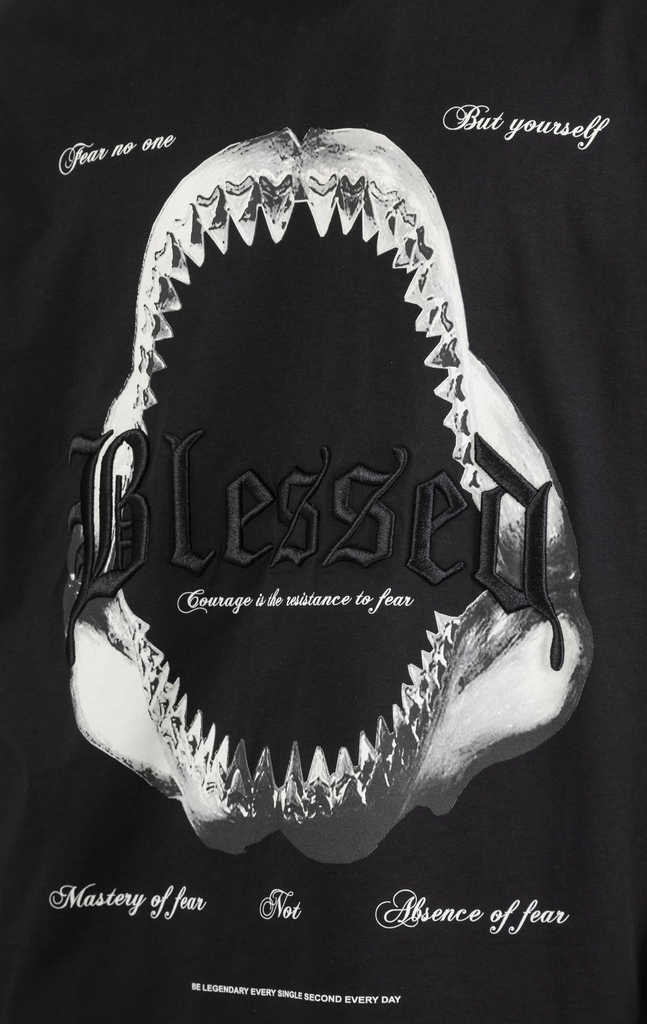 Men's boxy fit t-shirt in black. The shirt features dropped shoulders, longer sleeves, and a wide, fitted neck rib. It has a "Courage" front print with 3D embroidery. Made from 100% cotton jersey (190gsm). A "blessed" slogan is printed on the inner neck binding.