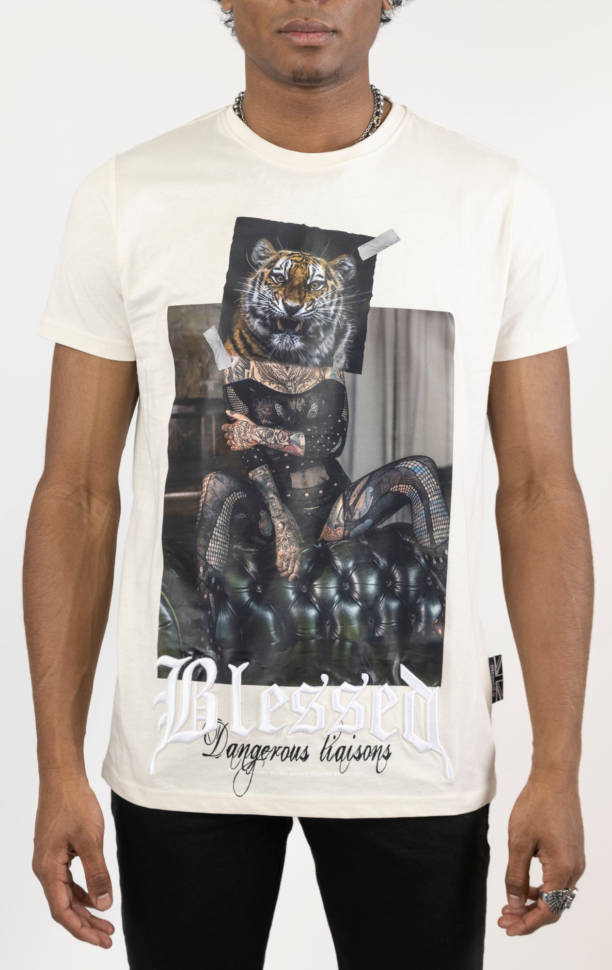 Men's regular fit t-shirt in eggshell color. The shirt features a slightly elongated sleeve, a fitted neckline, and a straight body. It has a "Dangerous Liaisons" front print with 3D embroidery. Made from 100% cotton jersey (190gsm). A "blessed" slogan is printed on the inner neck binding and a woven side seam tab with "blessed" is also included.