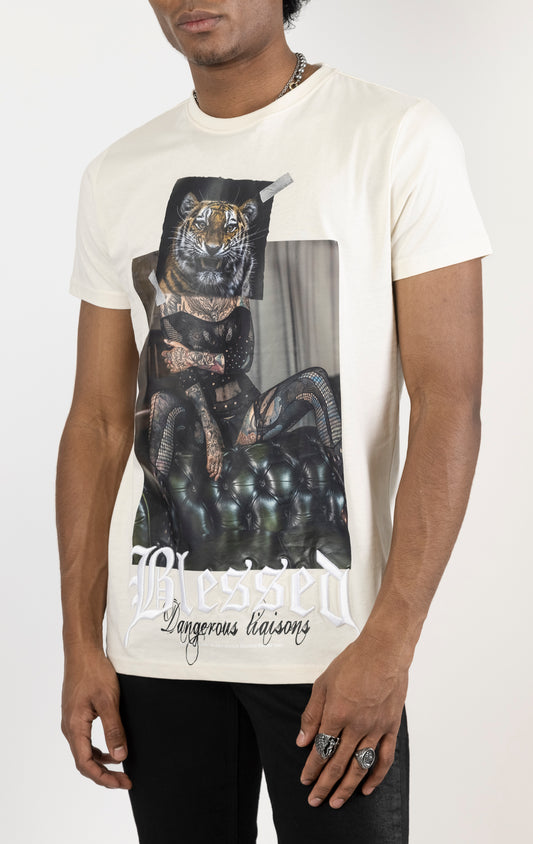 Men's regular fit t-shirt in eggshell color. The shirt features a slightly elongated sleeve, a fitted neckline, and a straight body. It has a "Dangerous Liaisons" front print with 3D embroidery.  Made from 100% cotton jersey (190gsm).  A "blessed" slogan is printed on the inner neck binding and a woven side seam tab with "blessed" is also included.