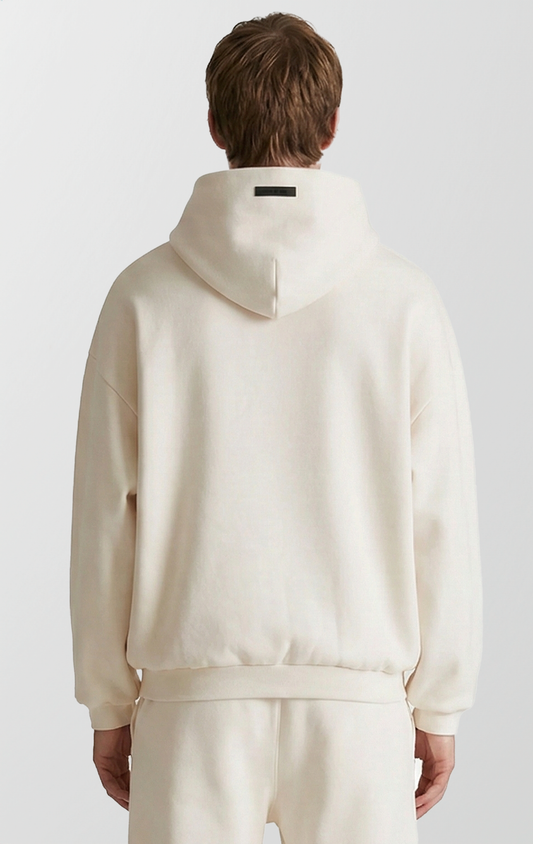 A solid-colored streetwear hoodie with a relaxed fit, dropped shoulders, and a small rubber brand label on the top of the hood.
